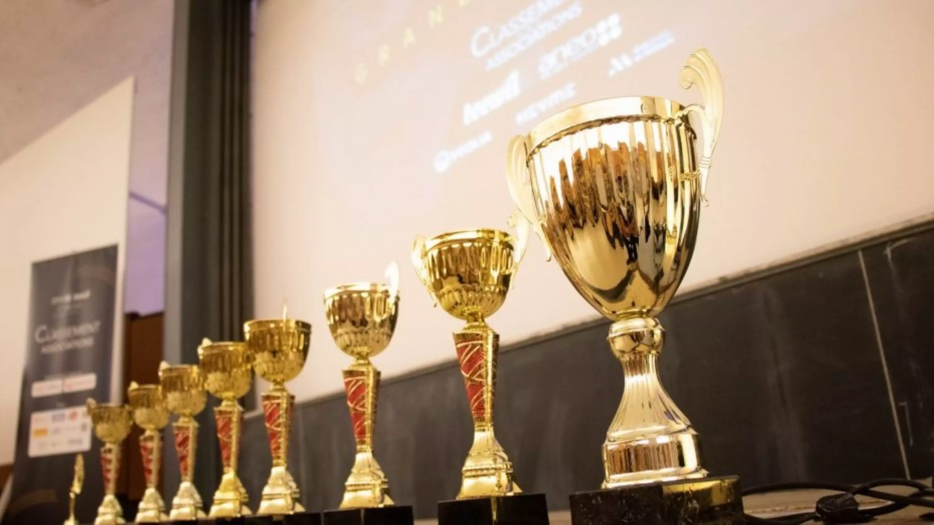 Les coupes pour les finaliste devant une projection du logo de l'association